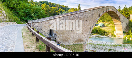 500 anni hog backed Rinascimento ponte di collegamento con singolo span due rive di un fiume di nuoto nella campagna italiana Foto Stock