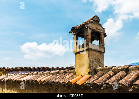 Il vecchio camino di una casa su una ceramica tetto di tegole Foto Stock