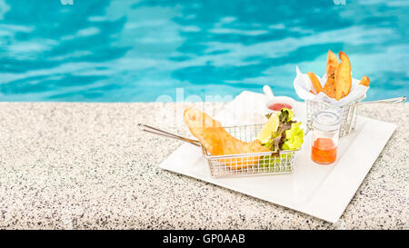 Pesce e patatine in quadrato bianco con piastra decorata, piscina. copia spazio. Foto Stock