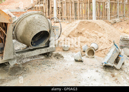 Vecchio cemento macchina miscelatrice con sabbia arresto carrello accanto a un sito in costruzione. Foto Stock