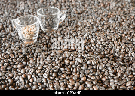 Chicchi di caffè tostati con sfocata 2 tazzine di caffè sul fondo. Foto Stock