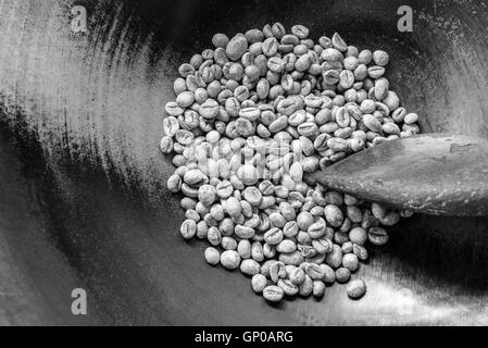 Chicchi verdi di caffè in padella con una vecchia ciotola di legno, pronti per essere arrostiti. Copia dello spazio. Foto Stock