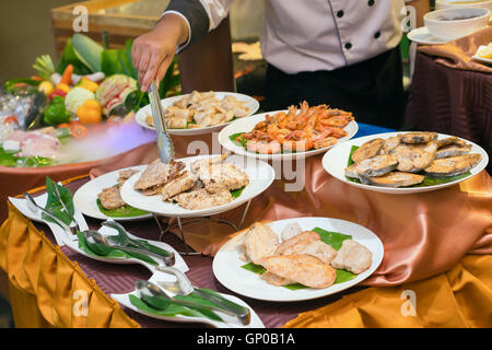 Lo chef prepara piatti di varie carni, carne di maiale, carne di manzo e di pollo, pesce, gamberi e calamari per la cena in un ristorante di lusso. Foto Stock