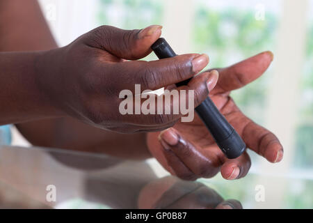 Il Test per il diabete donna utilizzando lancelet sul dito Foto Stock