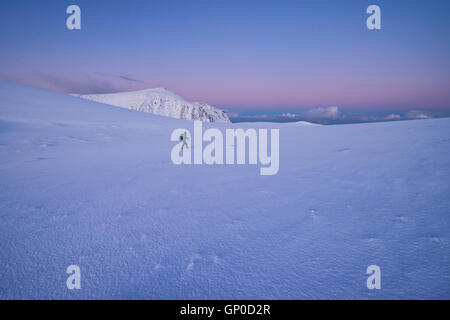 Escursionista femmina camminando per vuoto inverno paesaggio di montagna all'alba, Moskenesøy, Isole Lofoten in Norvegia Foto Stock