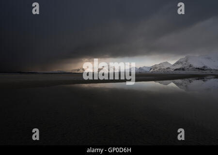 Nuvole scure di avvicinamento invernali storm coprire paesaggio di montagna da Ytresand beach, Moskenesøy, Isole Lofoten in Norvegia Foto Stock