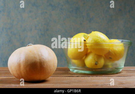 Zucca e una ciotola di vetro di limoni sul tavolo Foto Stock