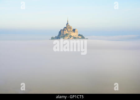 VISTA AEREA. Abbey su un picco isolato sopra la nebbia di mattina presto. Mont Saint-Michel, Manica, Normandia, Francia. Foto Stock