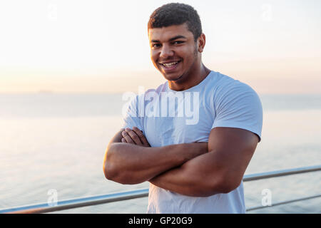 Felice americano africano giovane atleta in piedi con le braccia incrociate su sunrise Foto Stock