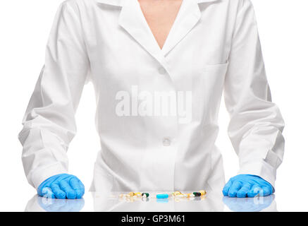 Pila di diverse compresse e capsule su tavola nella parte anteriore del medico donna in bianco camice blu e i guanti chirurgici Foto Stock