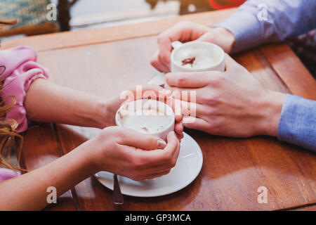 Persone di bere il caffè nella caffetteria, primo piano della giovane mani con coppe Foto Stock