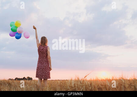 Il concetto di speranza, emozioni e sentimenti, donna con palloncini colorati nel campo, sfondo Foto Stock