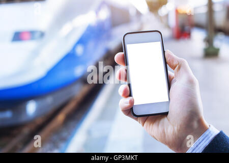 Mano azienda smartphone con vuoto nella schermata vuota nella stazione ferroviaria Foto Stock