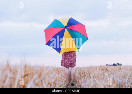 Donna con ombrello coloratissimo nel campo, ottimista positivo sfondo multicolore con copyspace Foto Stock