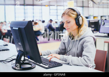 Istruzione degli adulti, donna di mezza età lo studio sul computer in biblioteca moderna Foto Stock