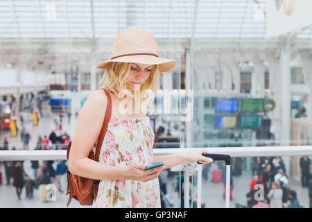 Donna in aeroporto per controllare il telefono cellulare e il viaggiatore app per smartphone Foto Stock