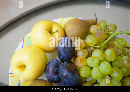 Piastra con frutta - mele, pere, prugne, uva. cibo sano concetto Foto Stock