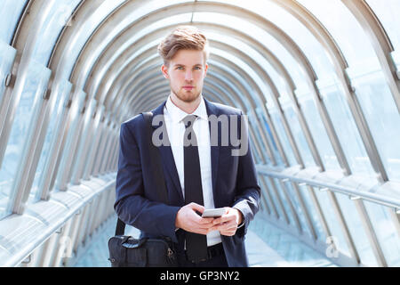Imprenditore a piedi in ufficio moderno corridoio, ritratto guardando la telecamera Foto Stock