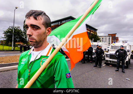 Un repubblicano irlandese uomo con una bandiera tricolore e indossando un Irlanda football shirt e set di Rosario, è impedito di camminare nella Belfast City Center tramite una linea di PSNI gli ufficiali di polizia Foto Stock