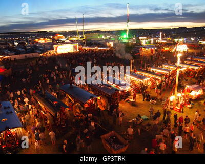 Grande Dorset Fiera a vapore di notte guardando verso il basso sulla Showmans motori di trazione tutto illuminato e la gente guardando intorno Foto Stock