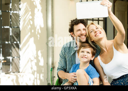 Famiglia con un bambino in posa per selfie prese con tavoletta digitale Foto Stock