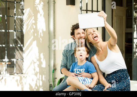 Famiglia con un bambino in posa per selfie prese con tavoletta digitale Foto Stock