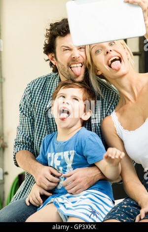 Famiglia con un bambino in posa per selfie prese con tavoletta digitale Foto Stock