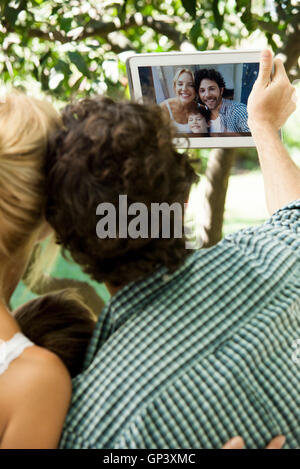 Famiglia con un bambino in posa per selfie prese con tavoletta digitale Foto Stock