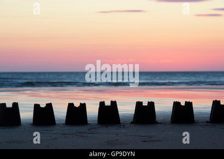 Linea di silhouette Sandcastles al sorgere del sole su una spiaggia. Northumberland, Inghilterra Foto Stock