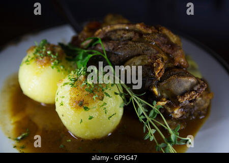 Un Schweinshax (maiale fuso a snodo) servita con gnocchetti di patate di Dresda, in Germania. Foto Stock