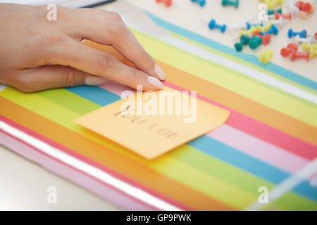 Mano umana tenendo nota adesiva con è possibile testo Foto Stock