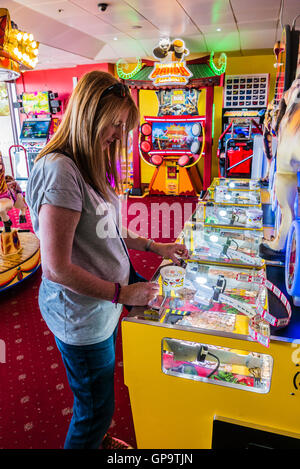 Una donna svolge un 'tuppenny nudger' (2p cursore) la macchina a un tradizionale mare divertimento arcade. Foto Stock