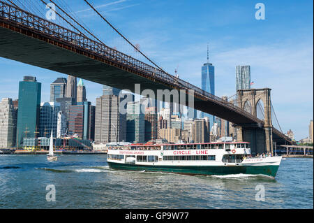 NEW YORK CITY - Agosto 27, 2016: Una Circle Line sightseeing barca porta i turisti sotto il ponte di Brooklyn per una gita. Foto Stock