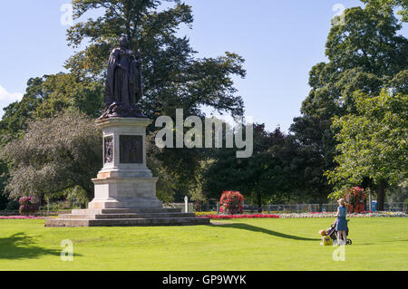 Una giovane donna con bambini guardando la statua della regina Victoria, in Bitte Park, Carlisle, Cumbria, England, Regno Unito Foto Stock