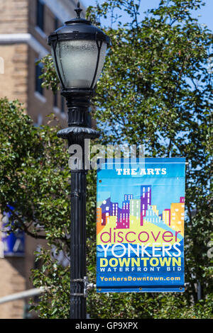 Un banner di promuovere il Yonkers Downtown Waterfront miglioramento del Business District pende da un lampione a Yonkers, New York. Foto Stock