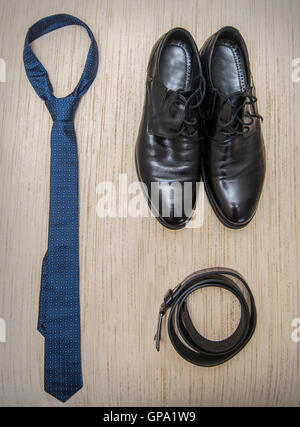 Set di abbigliamento e scarpe maschili su sfondo di legno. Accessori per gli uomini. Elegante nero pezzi isolati tavola bianco. Foto Stock