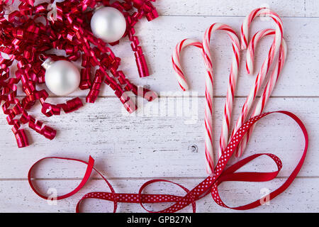 Nastri di natale, ornamenti e candy canes su bianco tavolo in legno con copia spazio. Foto Stock