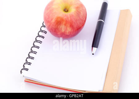 Un Apple su un blocco note contro uno sfondo bianco. Cibo sano concetto. Isolato sullo sfondo bianco. Foto Stock