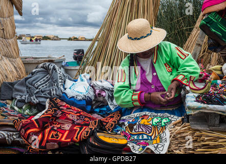 Irriconoscibile donna in costume nazionale indiani Uros maglieria un covone. Uros - isole galleggianti, Titicaca, Perù Foto Stock