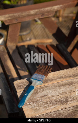 Dando una vecchia panca di legno un nuovo strato di conservante. Foto Stock