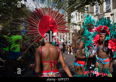 Parade ballerini in costumi di piume lunedì 28 agosto 2016 al carnevale di Notting Hill a ovest di Londra. Una celebrazione di West Indian / Caraibi cultura e pi grande deuropa street party, festival e la parata. Festaioli entrano nelle loro centinaia di migliaia di persone per divertirsi, danza, bere e lasciar andare nell'atmosfera brillante. Esso è guidato dai membri del West Indian / comunità dei Caraibi, particolarmente il Trinidadian e Tobagonian popolazione britannica, molti dei quali hanno vissuto nella zona fin dagli anni cinquanta. Il carnevale ha attirato fino a 2 milioni di persone in passato e centri intorno a una sfilata di carri allegorici, Foto Stock