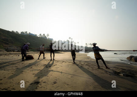 I pescatori alaggio in reti di sunrise, Vizhinjam spiaggia Kovalam, Kerala, India, Asia Foto Stock