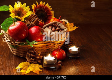 Autunno still life disposizione delle mele,dadi,candele,zucche e girasoli su scuro dello sfondo in legno Foto Stock
