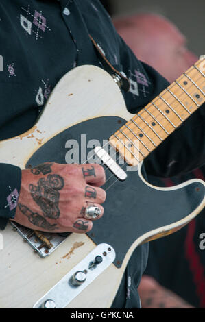 Tatuato mano con la parola RIDE sulle dita a suonare la chitarra su un rock and roll gig in Ace Cafe a Brighton motociclo evento. Foto Stock