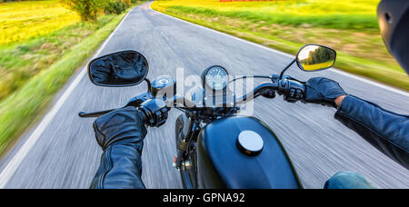 Conducente del motociclo equitazione sulla autostrada nella splendida luce del tramonto. Colpo da pillion vista driver Foto Stock