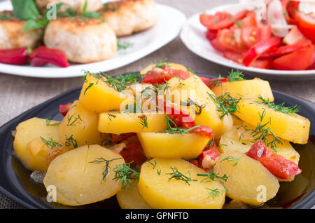Naturale cibi fatti in casa - Patate in umido con peperone, polpetta di carne macinata e insalata di pomodoro sul tavolo di cucina closeup Foto Stock