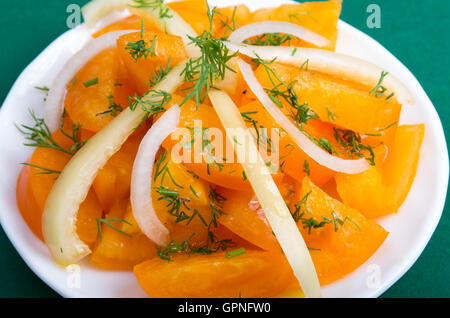 Insalata di materie orange pomodori e cipolle su uno sfondo verde closeup Foto Stock