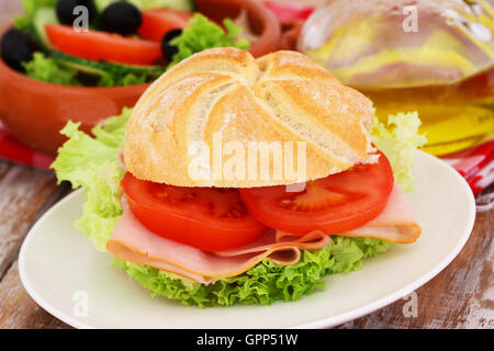 Pranzo composto da pane con pollo, pomodori e lattuga e ciotola di insalata Foto Stock