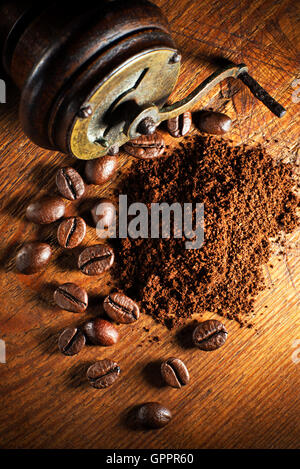Caffè macinato fresco con la smerigliatrice a mano su sfondo di legno. Foto Stock