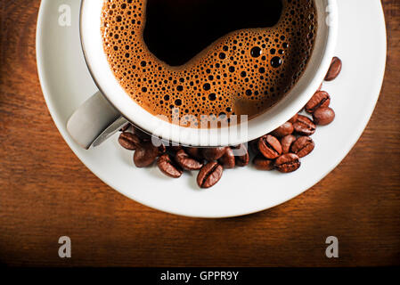 Tazza di caffè e fagioli su uno sfondo di legno. Foto Stock